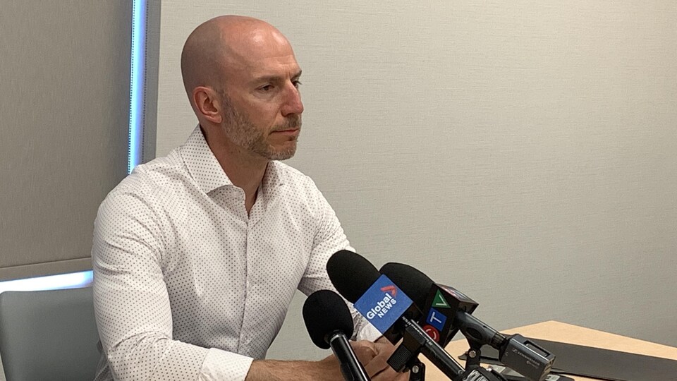 Un homme devant des micros lors d'une conférence de presse.