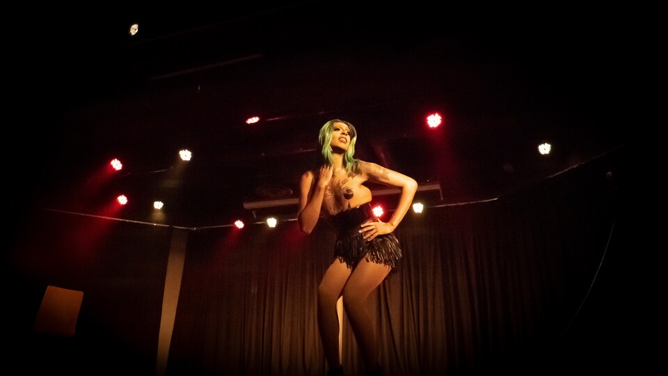 La drag queen Néona au centre d'une scène pendant un spectacle.
