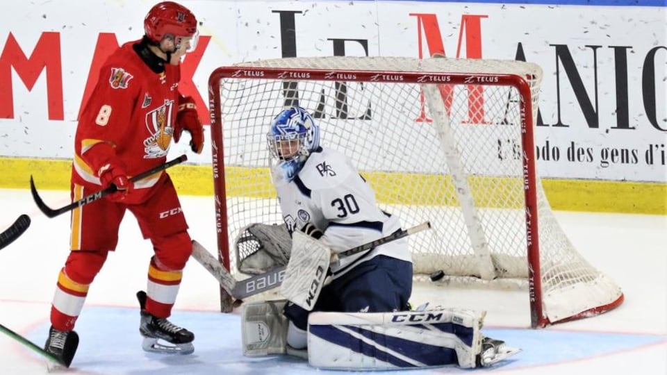 Un hockeyeur posté devant un gardien de but.