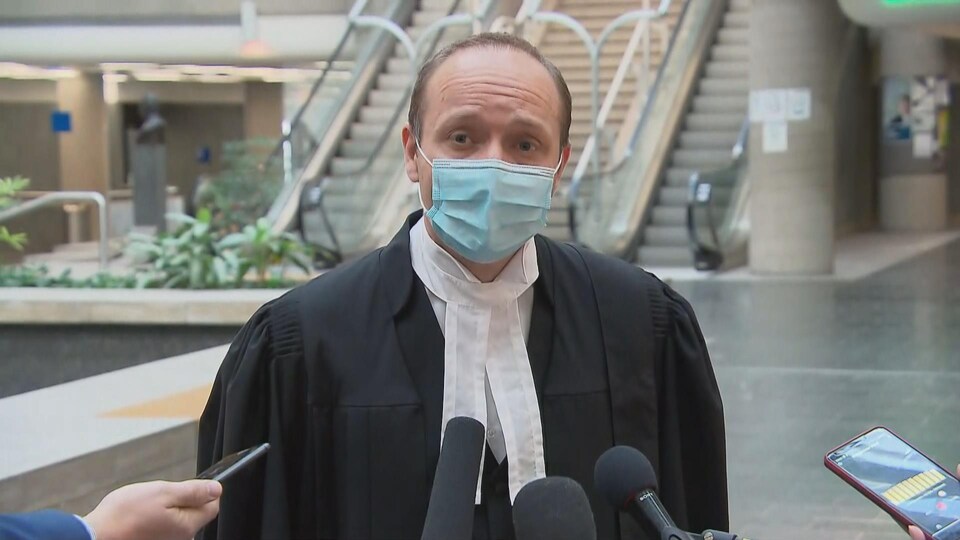 Me Godin wears a mask and speaks to the media in the central court of the Quebec City courthouse.