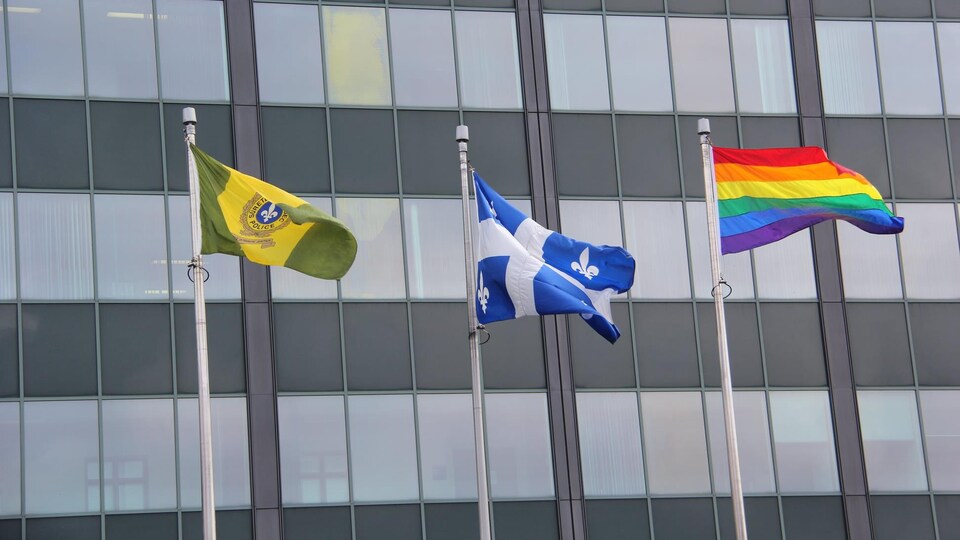 Le drapeau de la Sûreté du Québec, le drapeau du Québec et le drapeau arc-en-ciel.