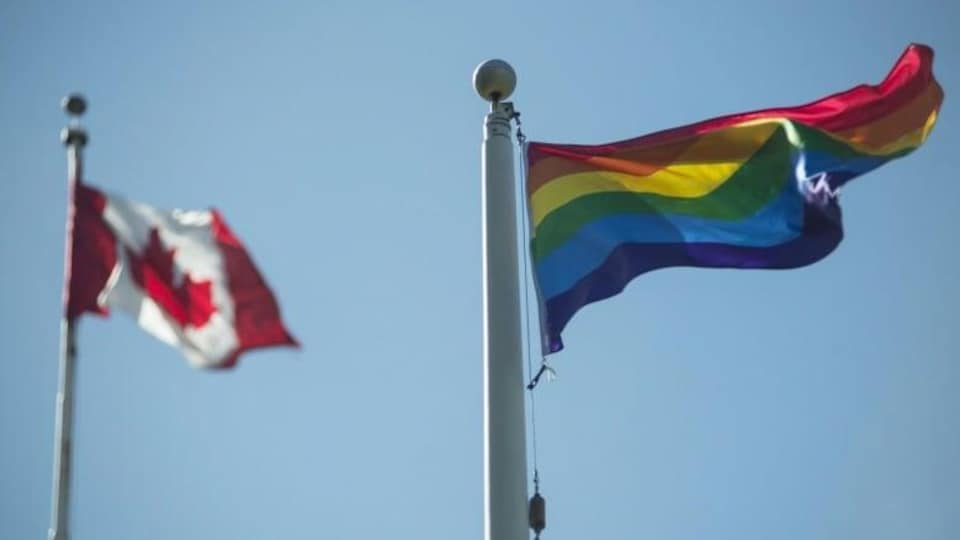 Le drapeau de la Fierté et le drapeau du Canada flottent au vent.