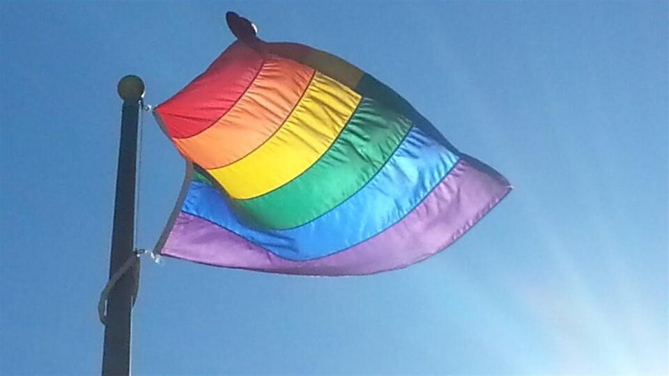 Un drapeau multicolore flotte au vent.