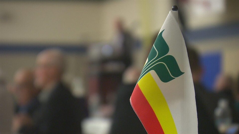 Le drapeau franco-manitobain flotte au-dessus d'une table.