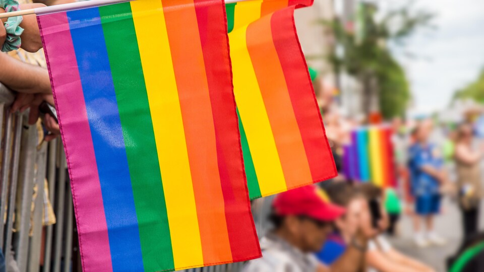 Des drapeaux gais pendent le long des clôtures lors du défilé de la fierté, à Montréal.