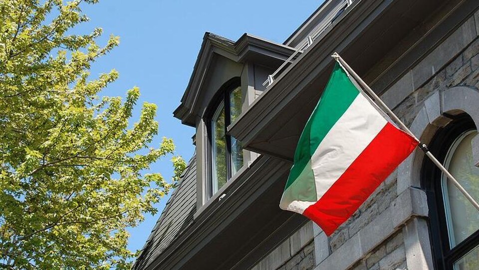 Drapeau patriote du Québec accroché sur la façade d'un bâtiment.