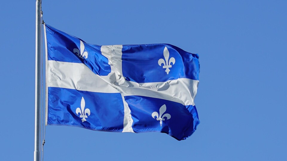 Le drapeau du Québec, au vent, sur un mât.