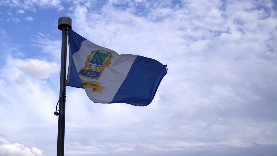 Le drapeau de la police de Trois-Rivières dans le ciel avec quelques nuages.