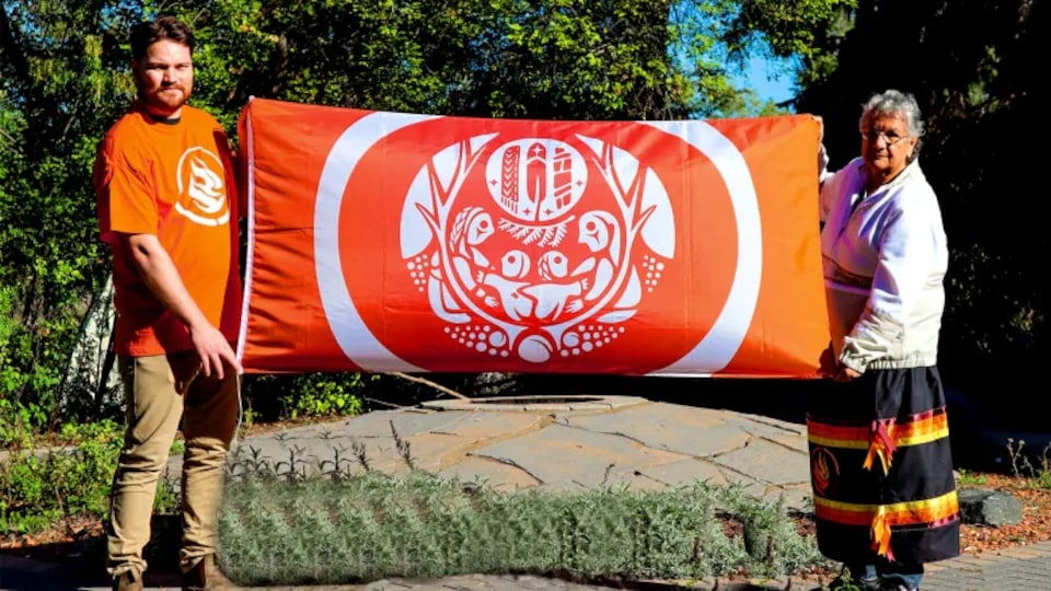 Deux personnes tiennent un drapeau orange.