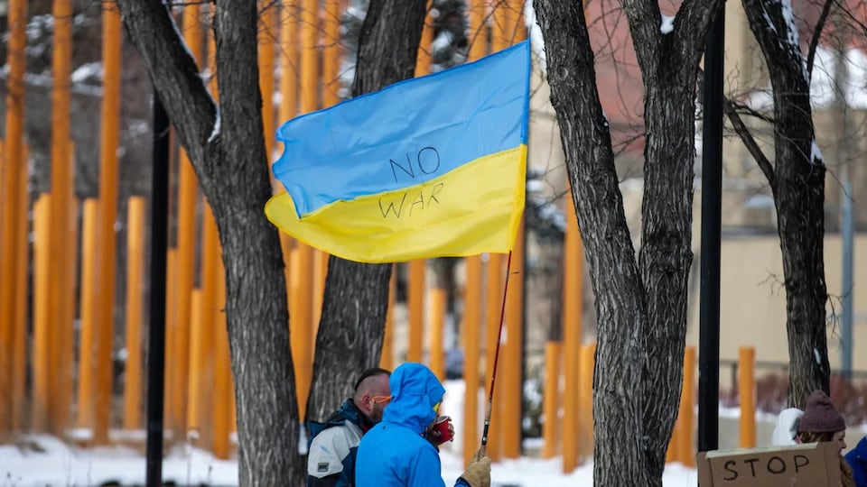 Un manifestant tient un grand drapeau ukrainien dans une main à Calgary.
