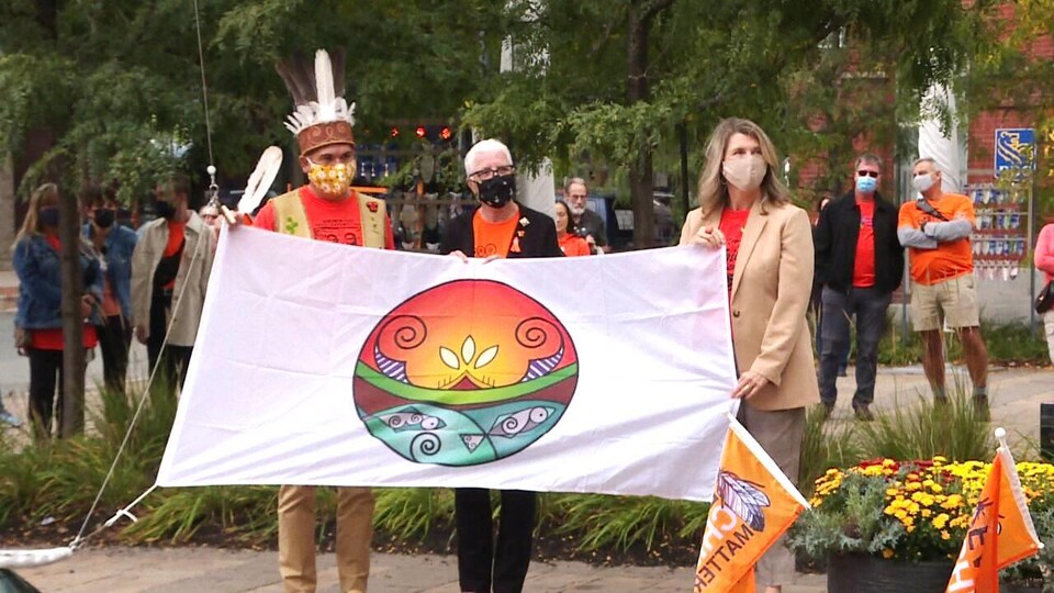 Trois personnes tiennent un drapeau wolastoqey.