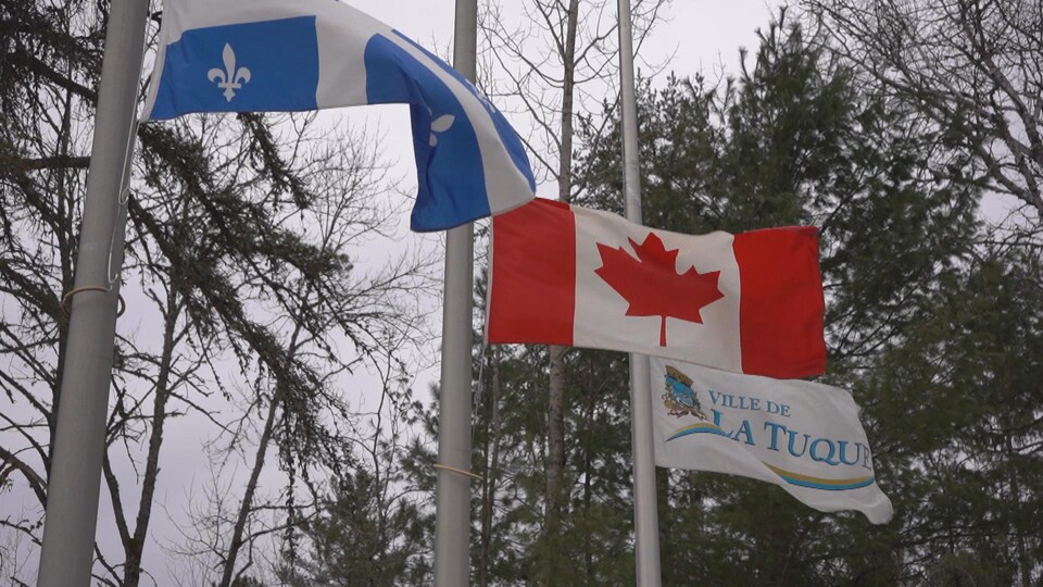 Les drapeaux du Québec, du Canada et de La Tuque, en berne.