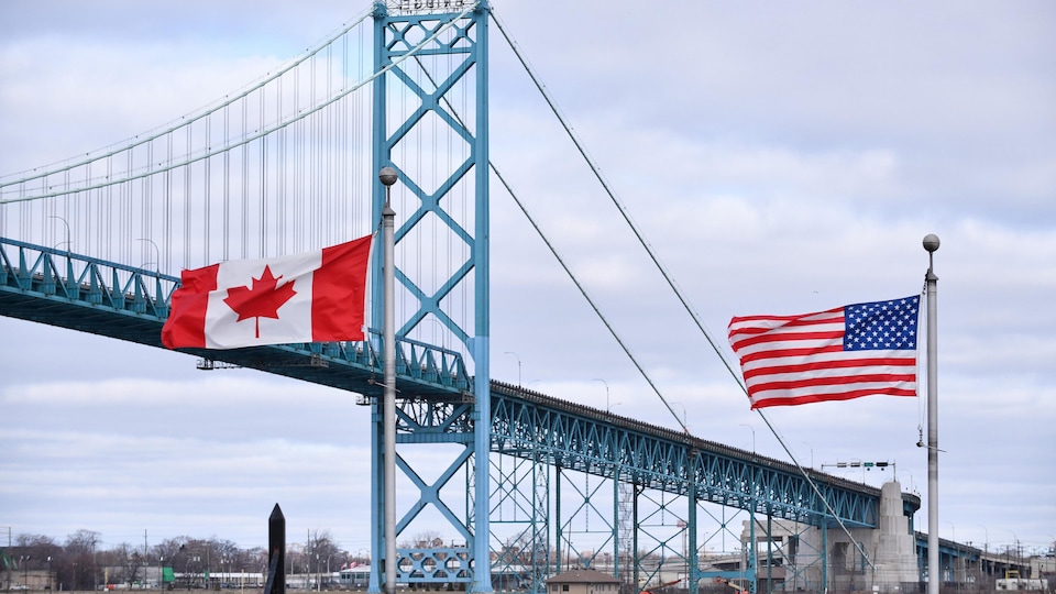 Les drapeaux du Canada et des États-Unis flottent devant le pont Ambassadeur.