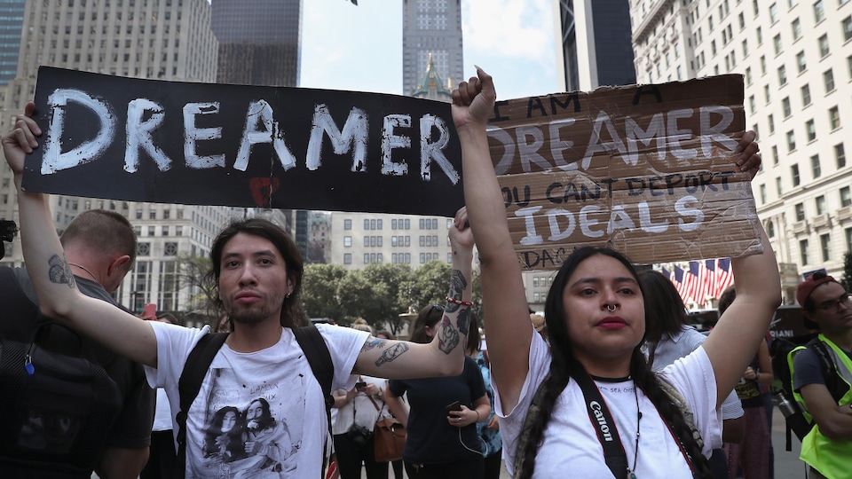 Deux jeunes tiennent des pancartes sur lesquelles sont écrits des slogans en faveur des Dreamers.