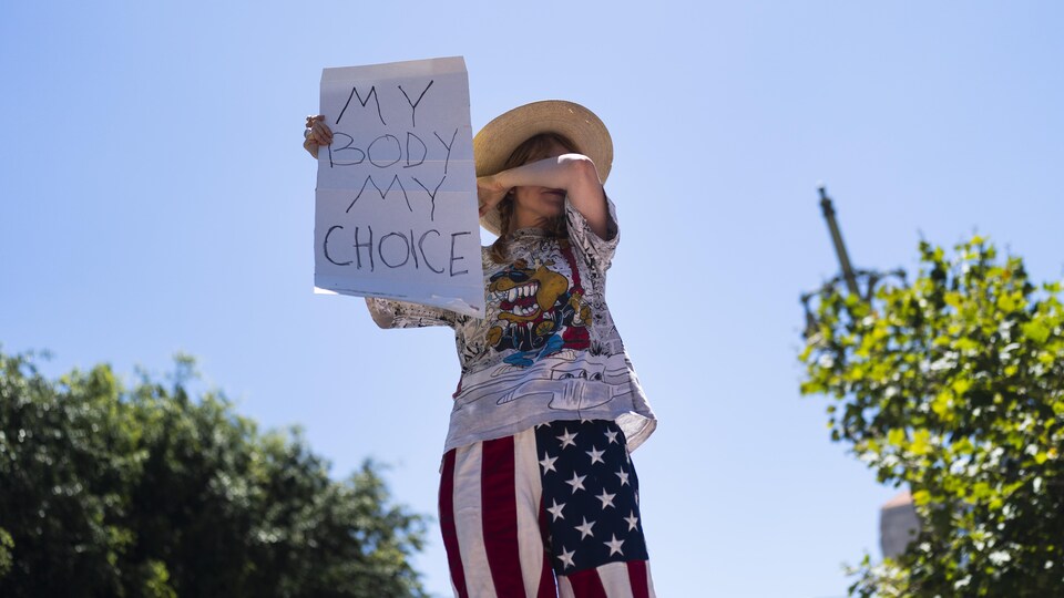 Une militante en faveur de l'avortement pleure en tenant une pancarte.
