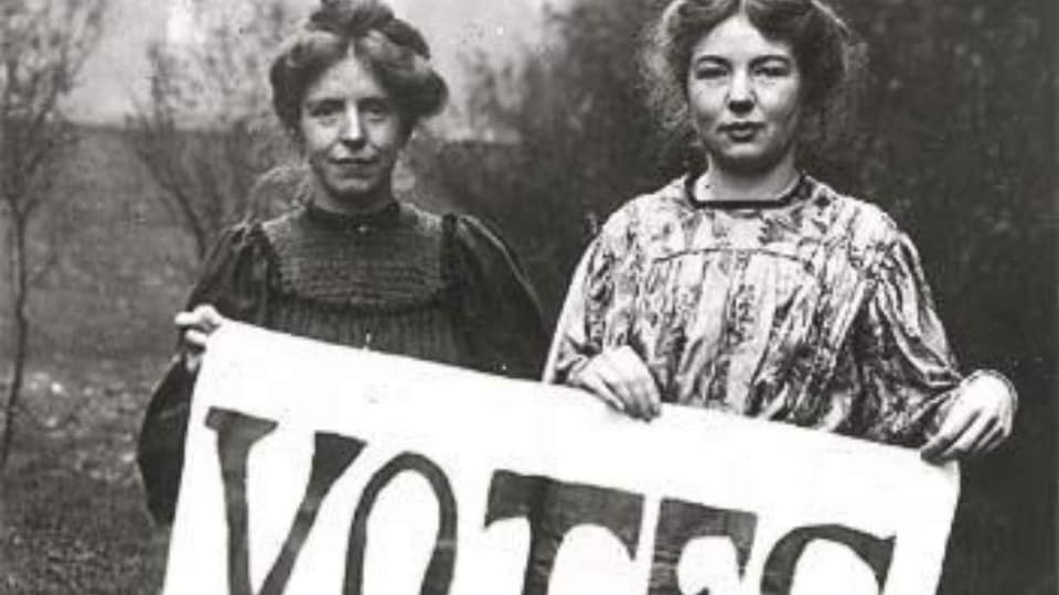 Deux femmes tiennent une pancarte pour le droit de vote des femmes.