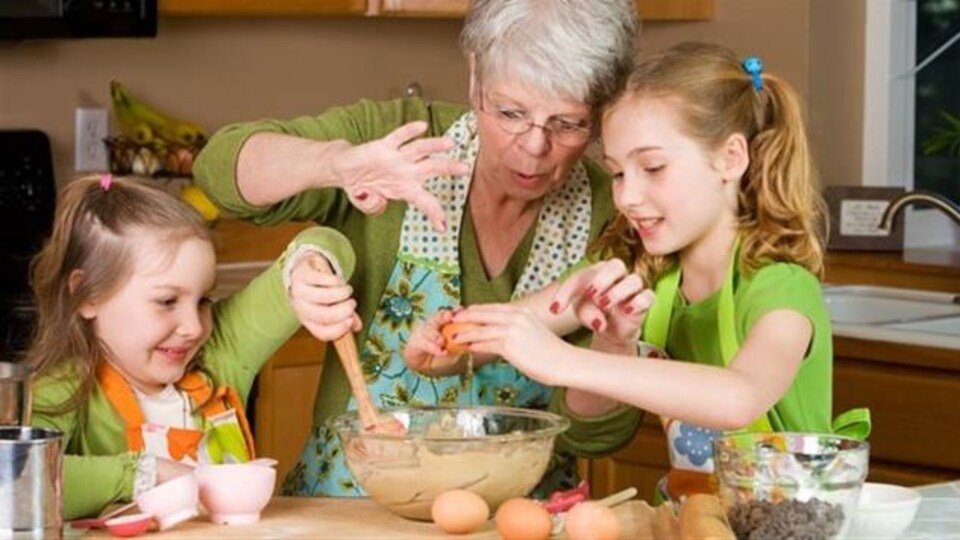 Une grand-mère et ses deux petites-filles qui font de la cuisine.