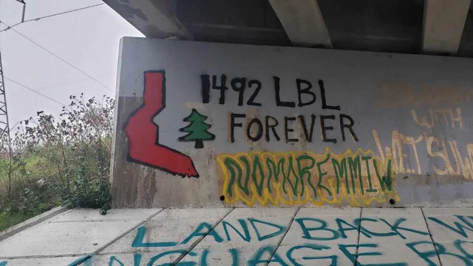 Des slogans peints à la bombe sous un pont.