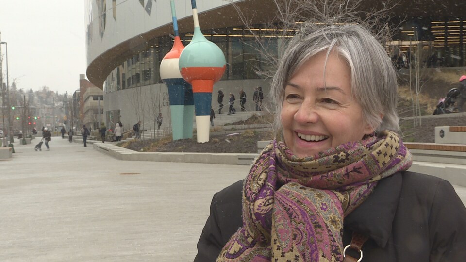 Druh Farrell, souriante, devant la bibliothèque centrale de Calgary, sous une averse de neige.