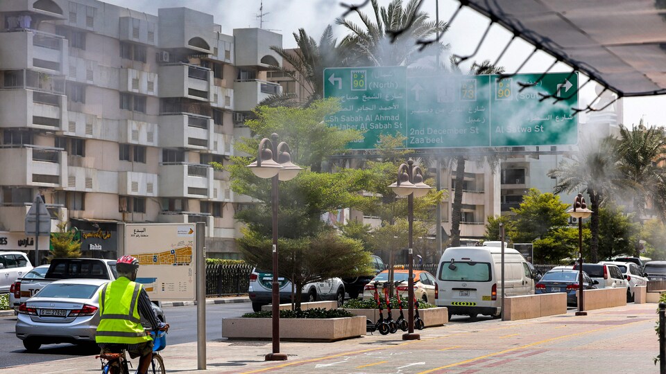 Des arroseurs libèrent de la vapeur d'eau dans une rue de Dubaï pour soulager les piétons en pleine canicule.