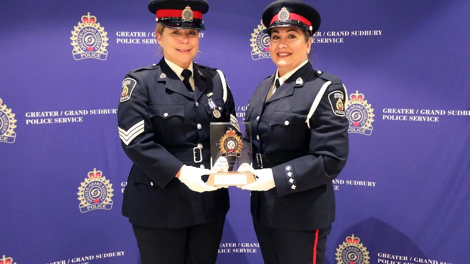 Deux femmes policières tiennent un trophée dans leurs mains.