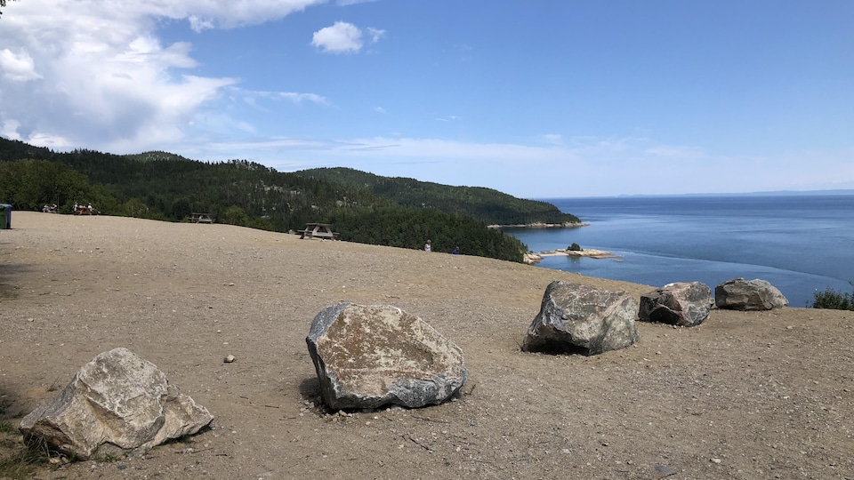 Des roches placées sur une colline de sable qui fait face à la mer.