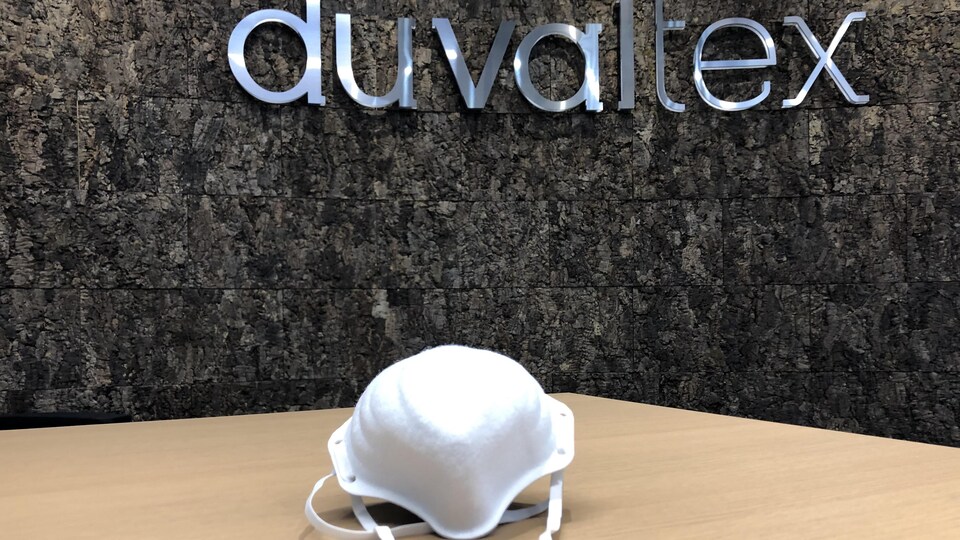 Un masque sur une table avec le logo de Duvaltex en arrière plan.