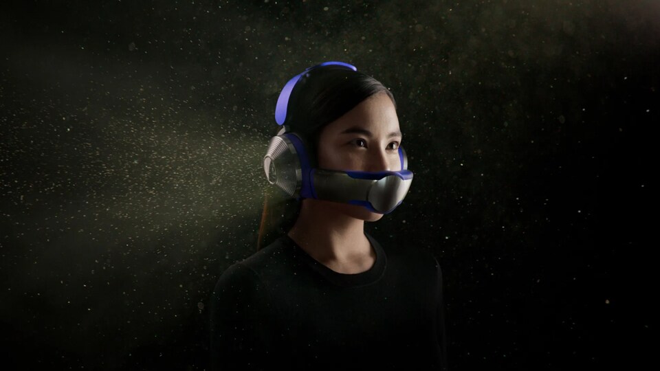 Une femme porte un casque d'écoute auquel est attaché un masque technologique qui purifie l'air.