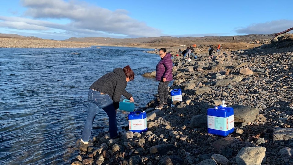 Des habitants d'Iqaluit remplissent des bidons d'eau à la rivière Sylvia Grinnell.