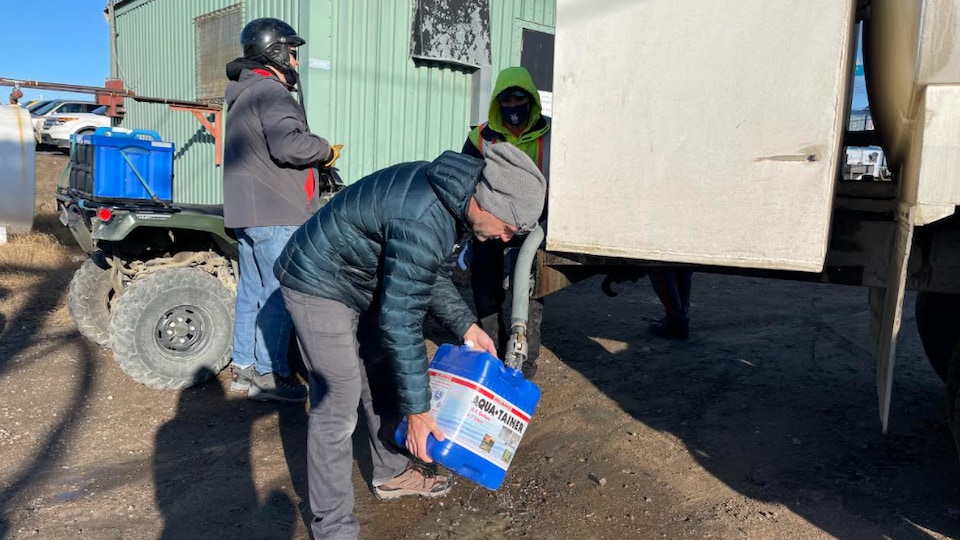Un homme remplit son bidon d'eau à partir d'un camion-citerne.