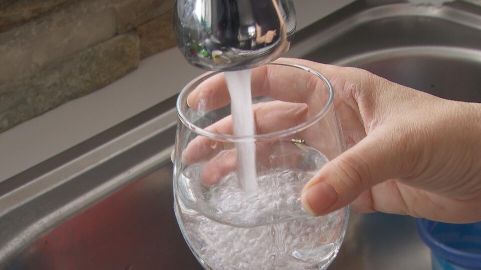 De l'eau coule du robinet dans un verre