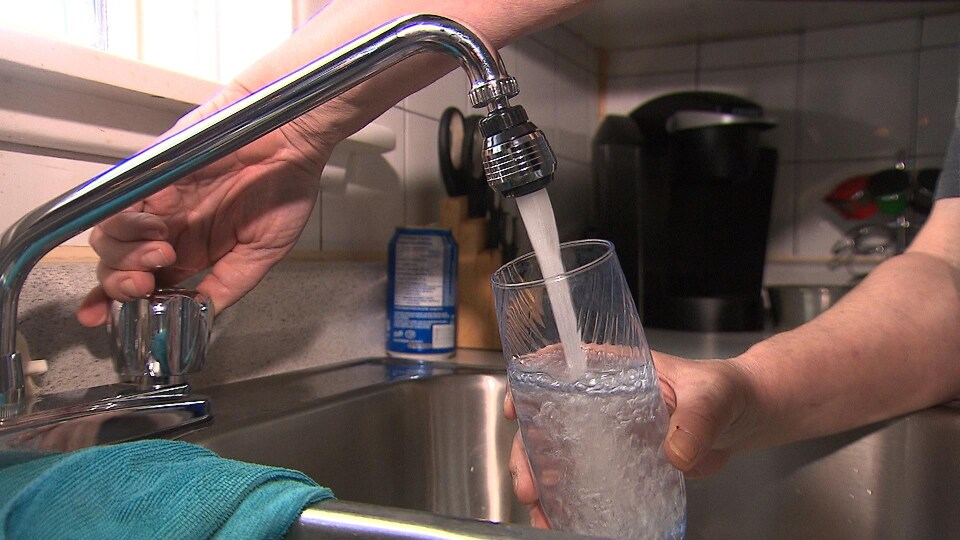 Une personne remplit un verre d'eau