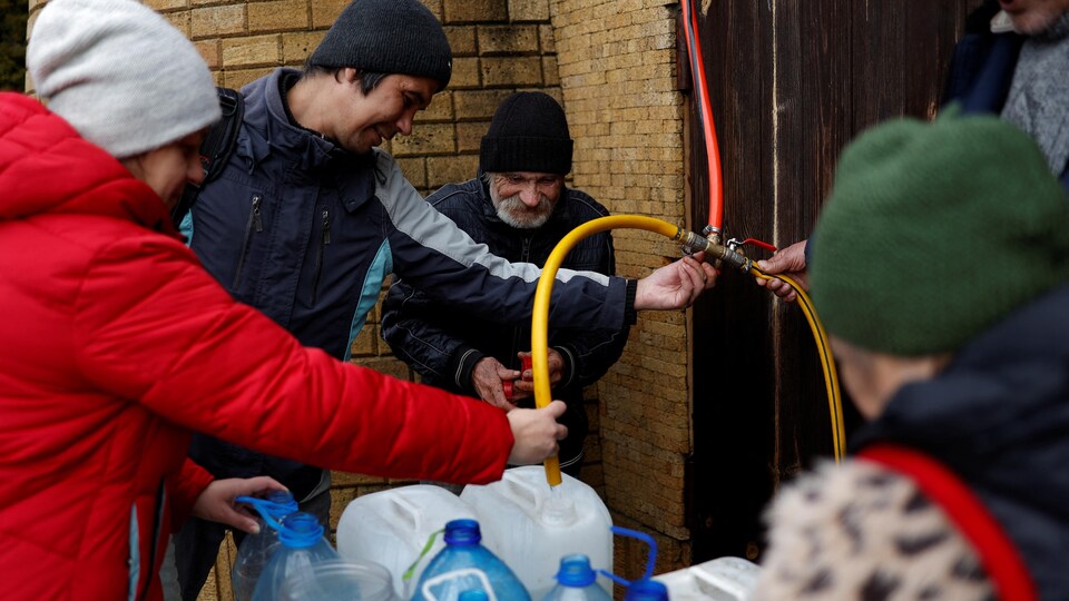 Des Ukrainiens remplissent des Jerricans d'eau.