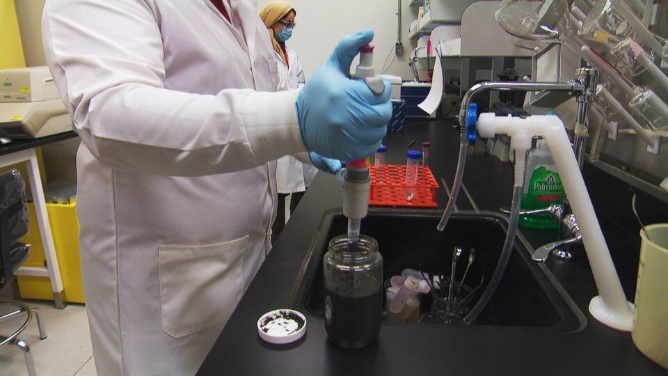 Un chercheur avec des gants dans un laboratoire.