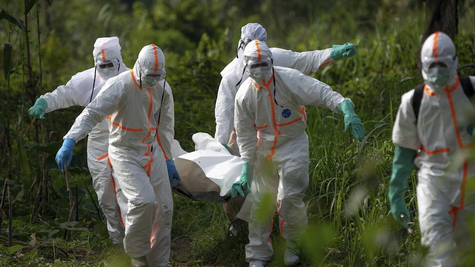 Des travailleurs funéraires en vêtements de protection portent les restes d’un homme mort d'Ebola.