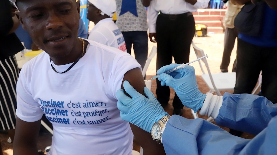 Un homme est vacciné. Il porte un t-shirt sur lequel on peut lire « Vacciner, c'est aimer. Vacciner, c'est protéger. Vacciner, c'est sauver. »