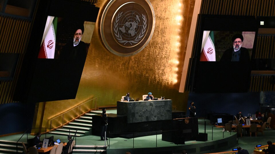 Dans une salle de l'ONU où se tient l'Assemblée générale, deux écrans montrent le discours du président iranien Ebrahim Raïssi.
