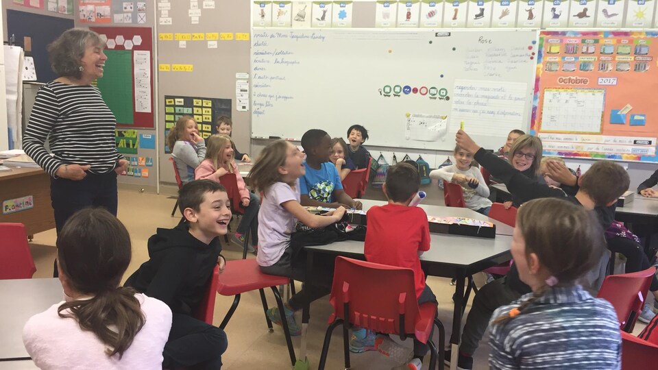 Des élèves de 3e année rient et participent à une activité en français dans leur salle de classe en s'amusant.