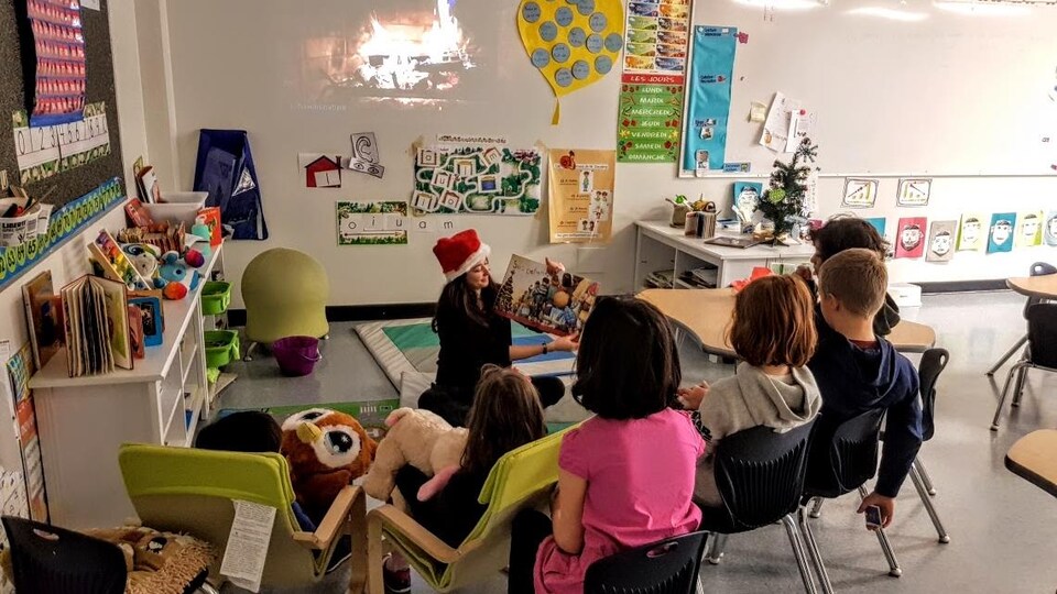 Une enseignante lit un livre à des élèves dans une salle de classe.