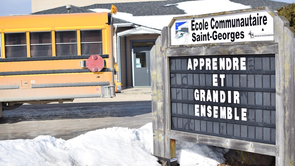 Le panneau de l'École communautaire Saint-Georges avec l'autobus scolaire en arrière-plan.
