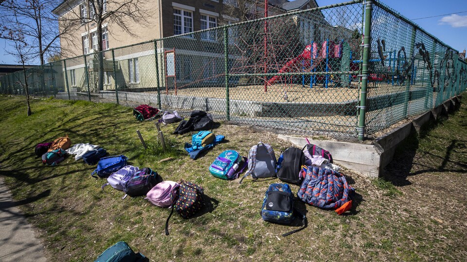 Des sacs à dos sur la pelouse d'une école.