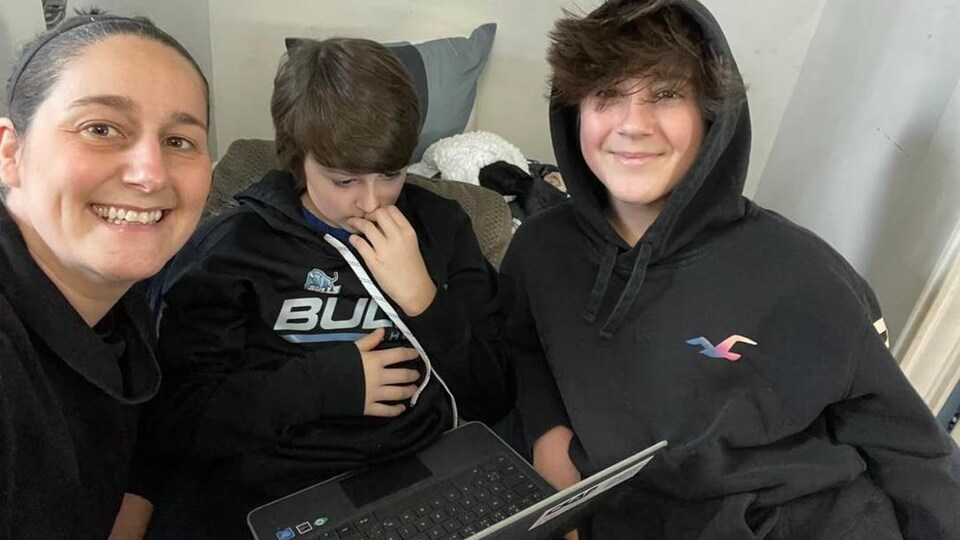 La maman et les deux garçons sont assis devant un ordinateur.