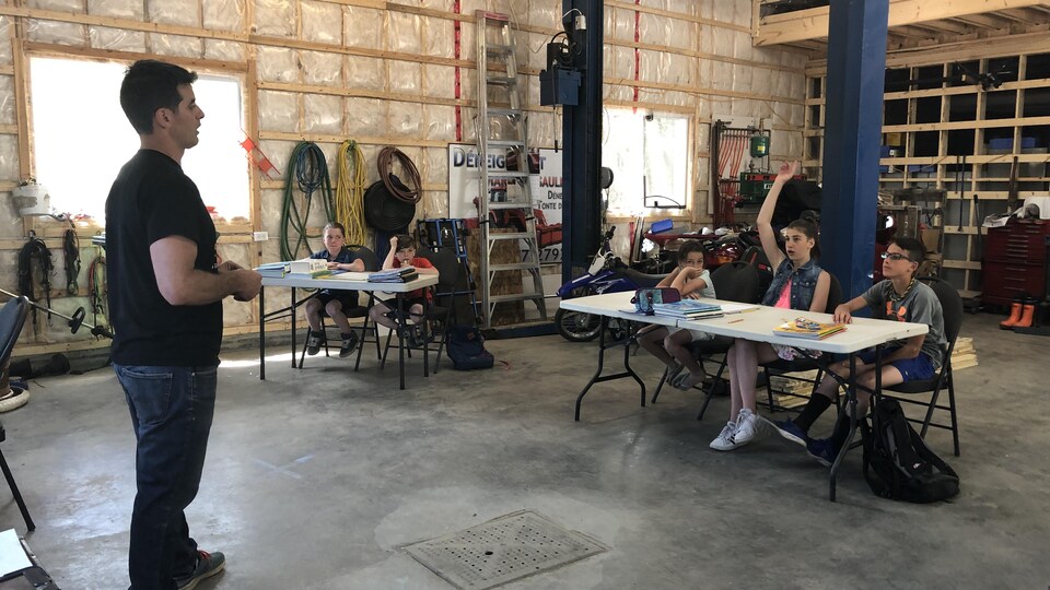 Un enseignant devant ses élèves dans un garage transformé en classe.