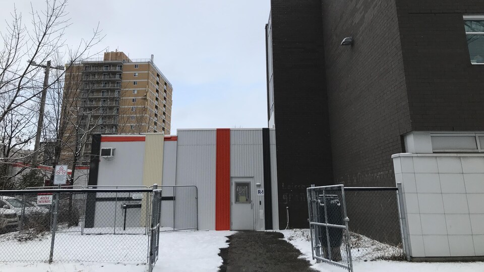 Un module de tôle grise et orange apparaît attaché à l'édifice central de l'école de la Grande-Hermine. 