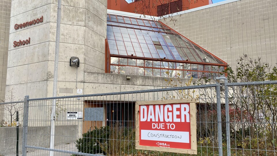 Une affiche disant : « danger, construction» devant l'école.