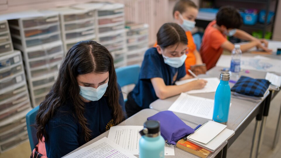 Des élèves assis à leur bureau complètent un exercice en français.