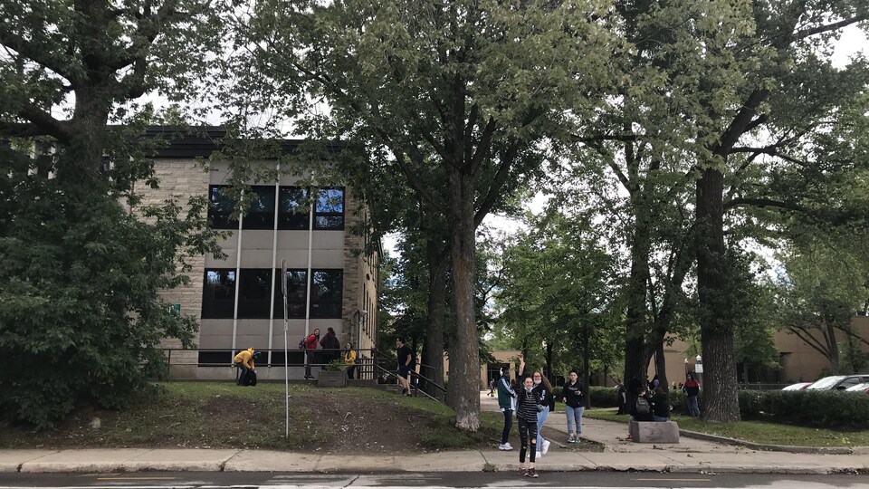 Un groupe d'élèves de l'autre côté d'une rue avec, en arrière-plan, une école