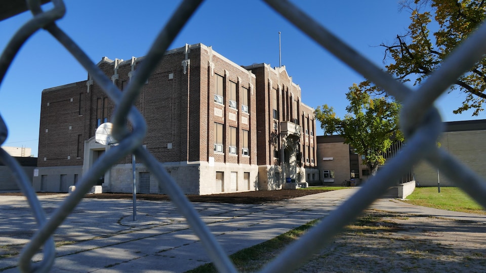 L'école est vue à travers la clôture de sa cour extérieure.