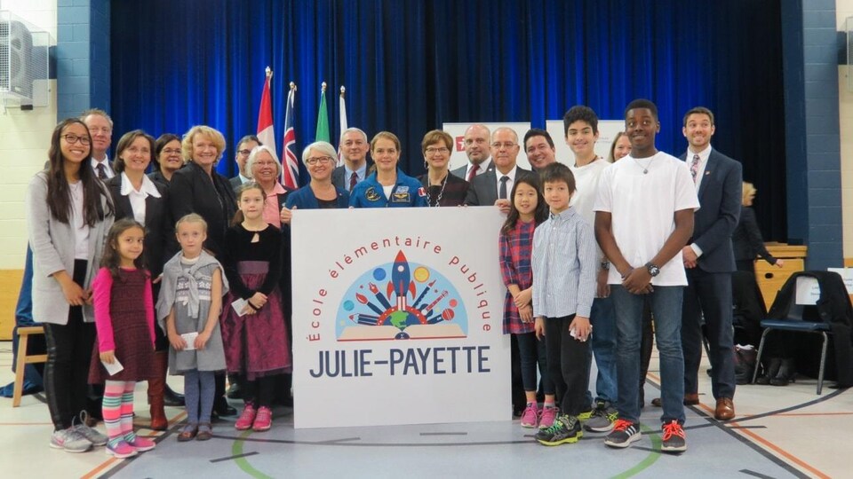 Julie Payette pose avec des enfants et du personnel dans une école.