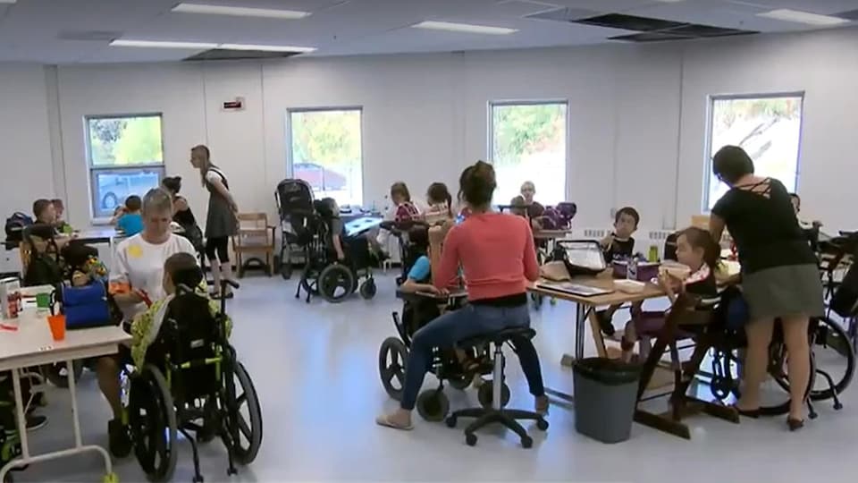 Des élèves handicapés et des intervenants à l'intérieur d'une salle de classe sur l'heure du dîner.